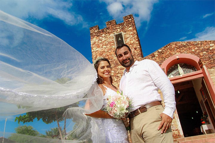 Casal de noivos em frente a igreja de pedra de Jericoacoara no dia de seu casamento