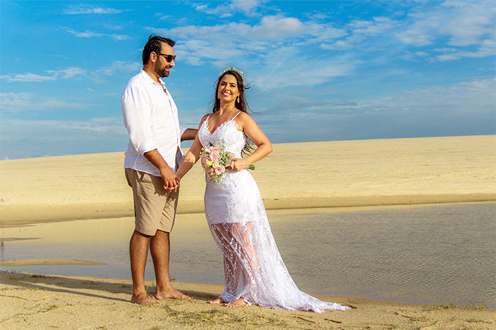 Casal de noivos de mãos dadas na duna de areia de Jericoacoara