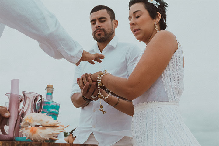 Casal de noivos e celebrante na praia