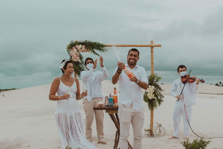 Casal estourando champanhe na praia