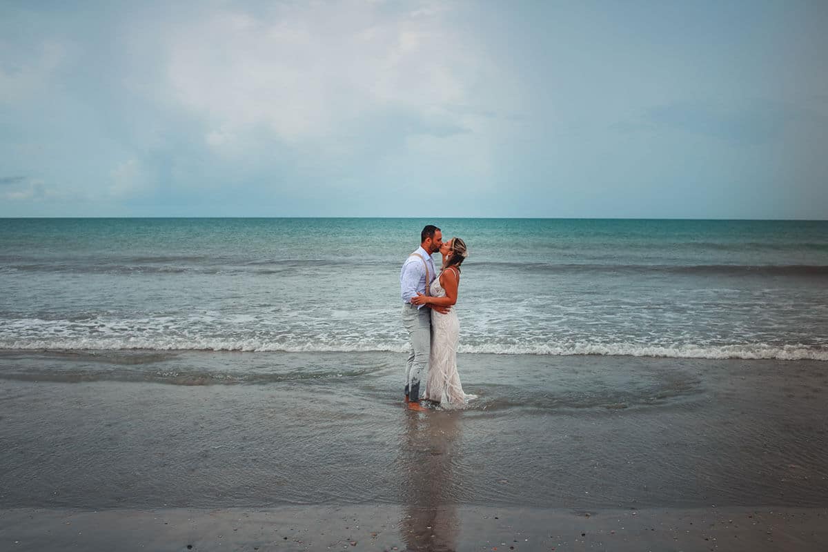Casal de noivos se beijando na praia