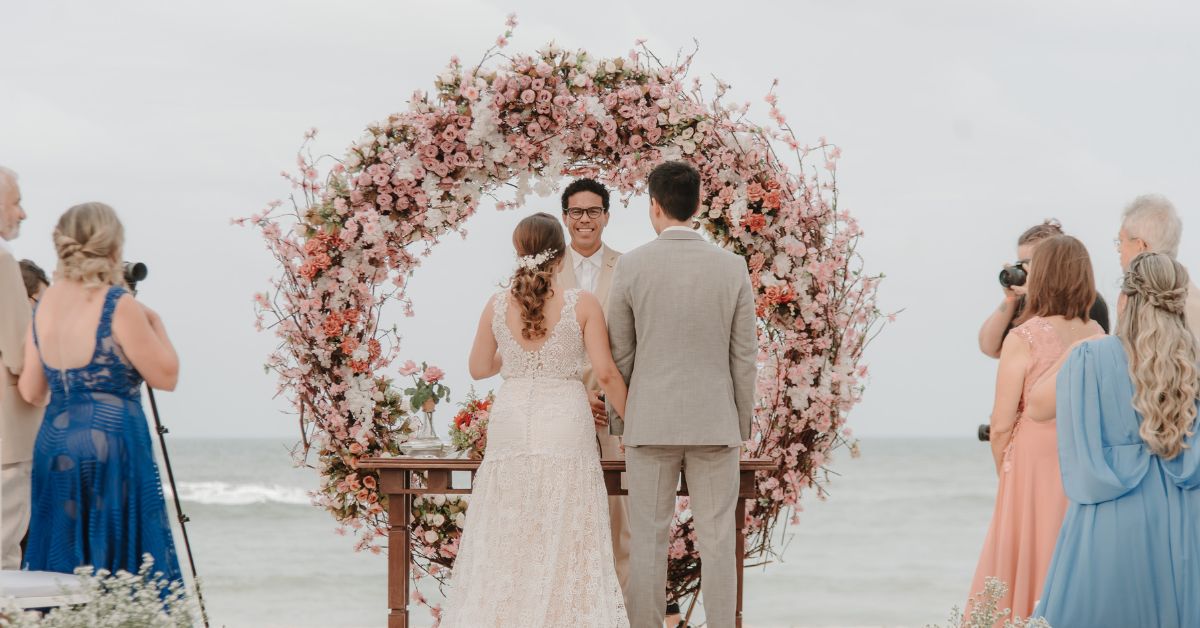 Cerimônia de casamento na praia com decoração, noivos e celebrante