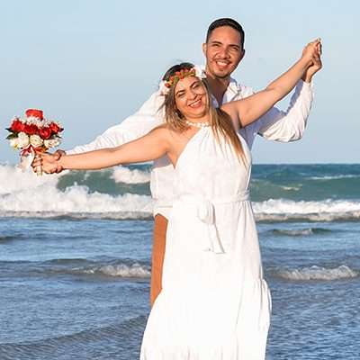 Depoimento-noiva-Izabela-Miranda-celebrante-Ed-Rodrigues Homem e mulher em pé, na beira da praia comemorando casamento