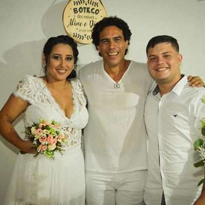 Noiva Aline Maria Noiva segurando buquê de flores, abraçada com celebrante do casamento e o noivo