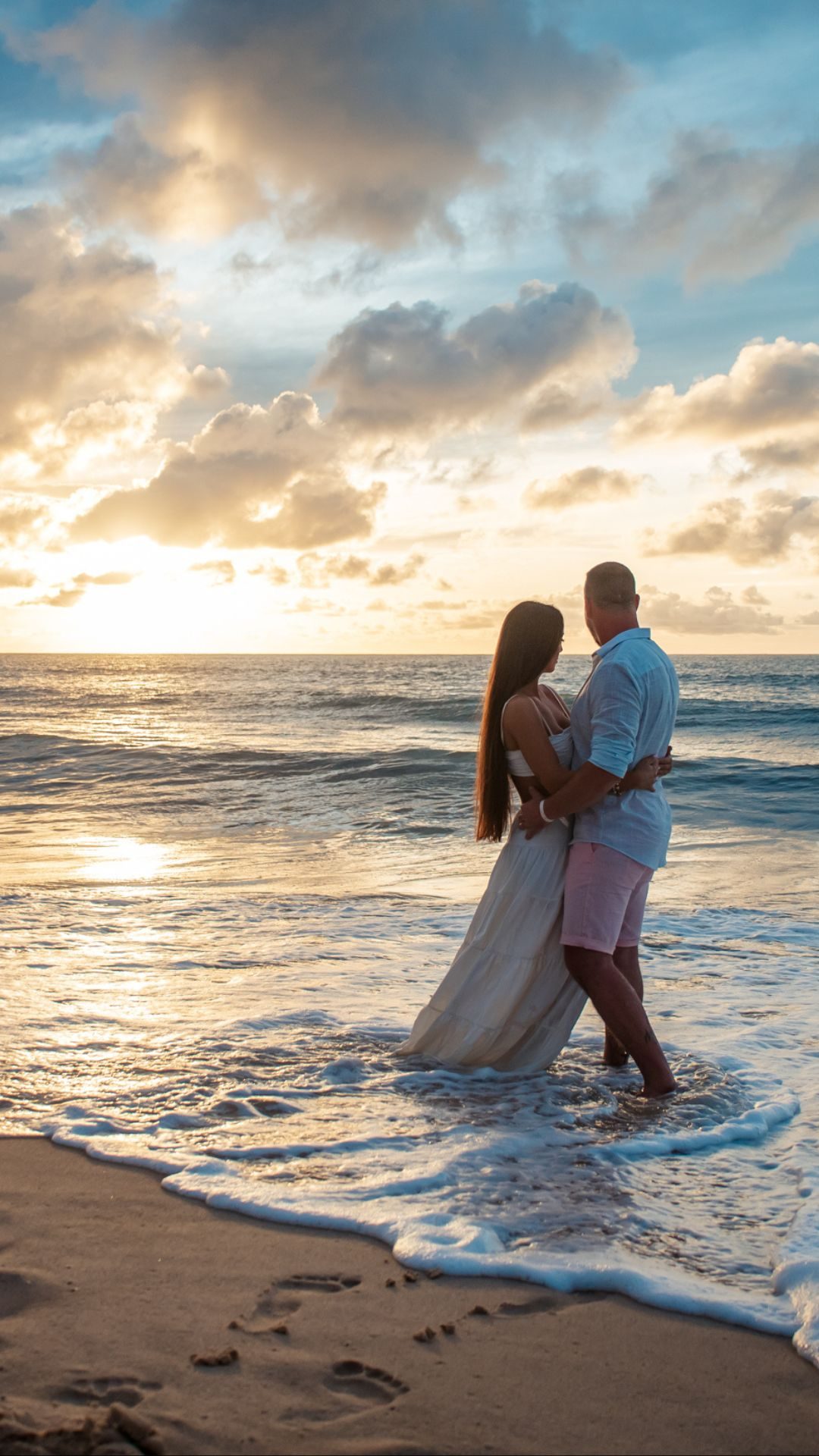 Casal de noivos abraçados na praia, no pôr do sol