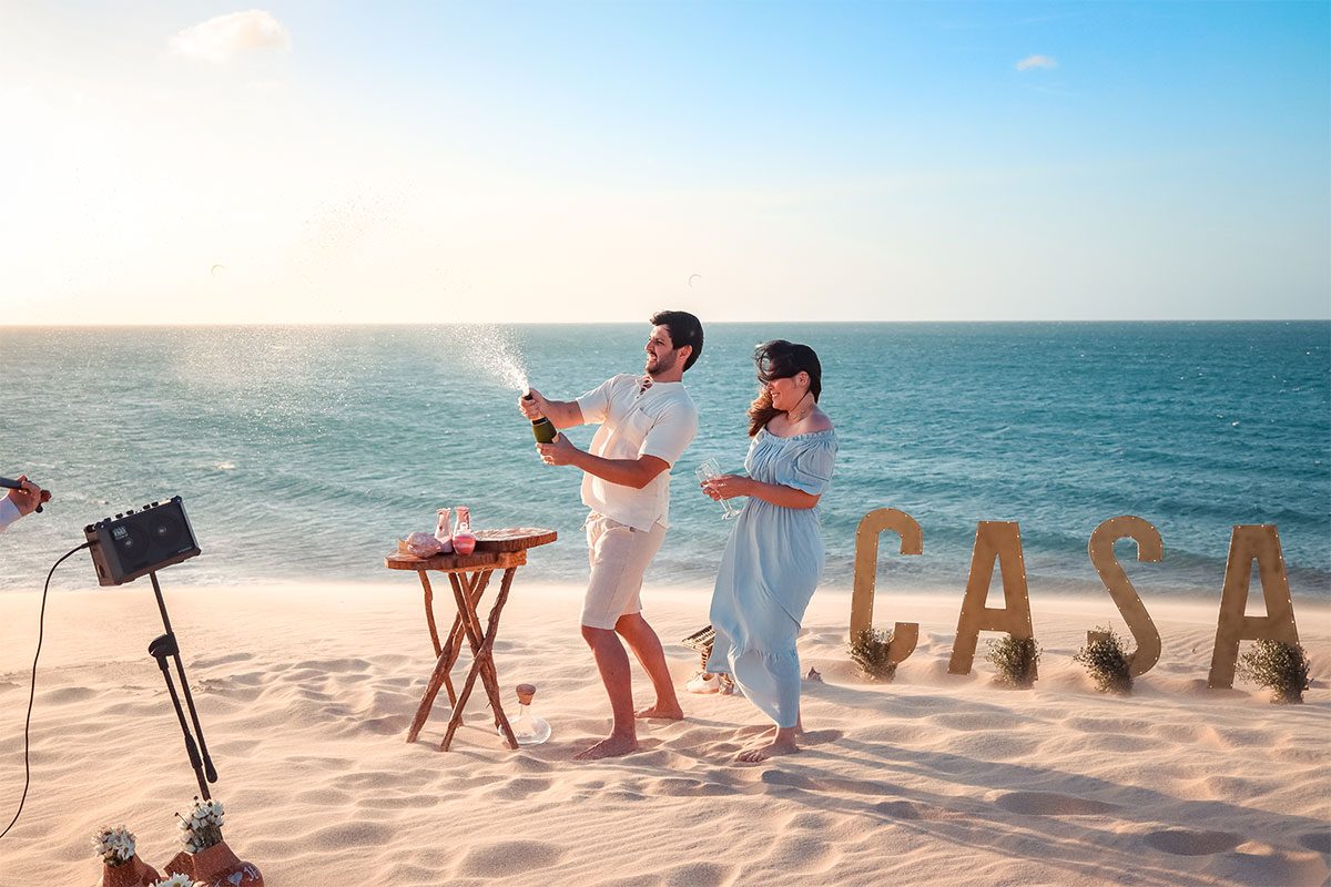 Casal brindando na praia com champanhe