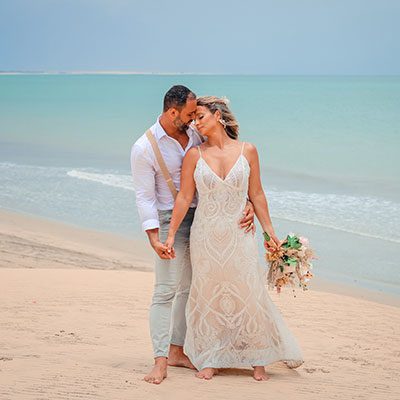 Noiva e noivo abraçados na praia